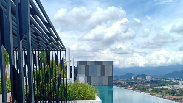 An infinity pool with a wooden deck and a modern building in the background. - The Horizon by MyKey (Ipoh)