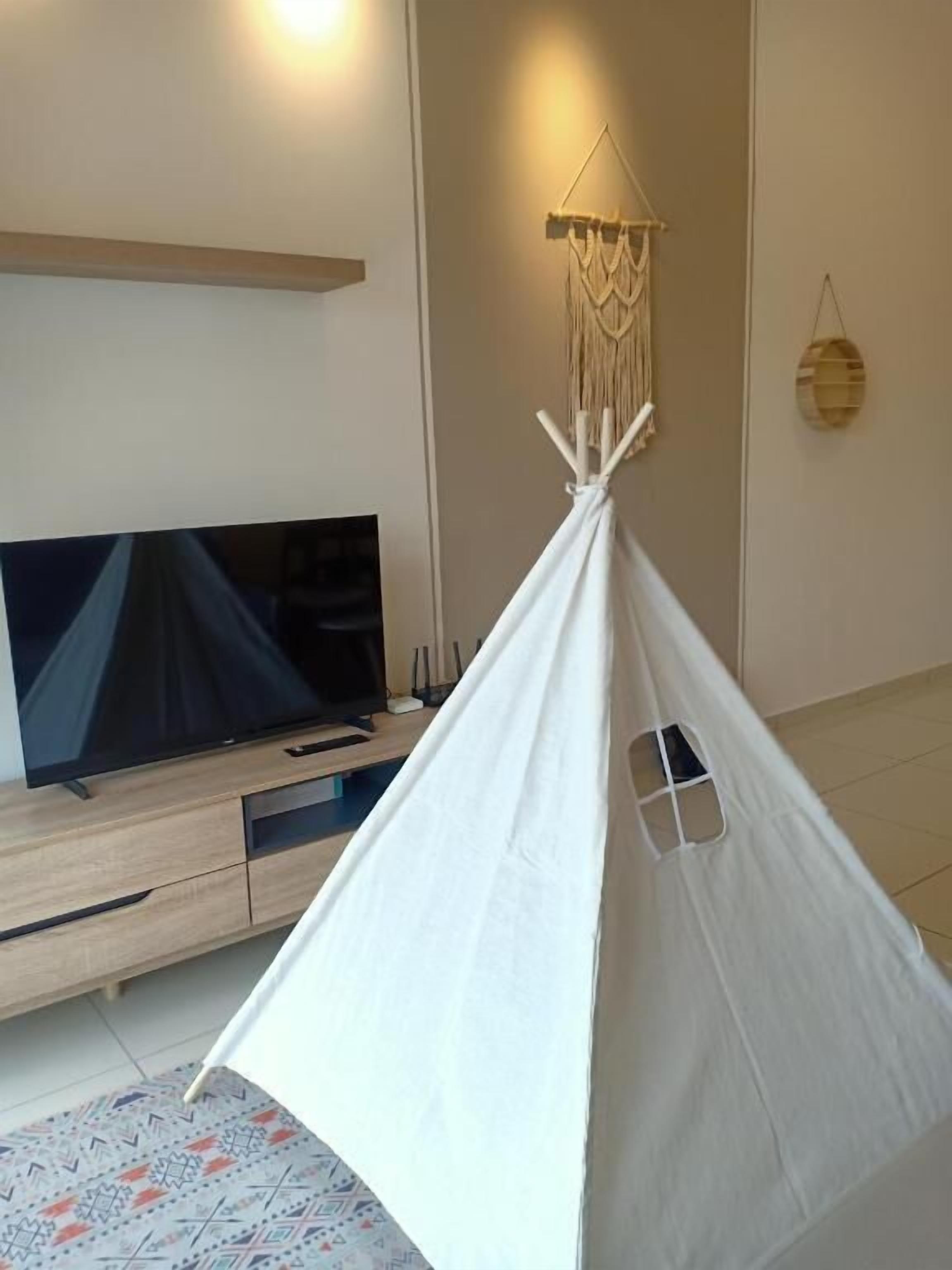A white teepee tent in a living room with a television and wooden furniture.