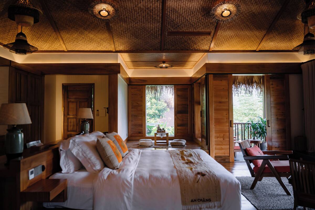 Un dormitorio amplio con una cama grande, lámparas de noche, una mesita pequeña y vistas al exterior.