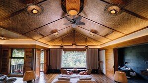 Une chambre spacieuse avec un grand lit, deux tables de chevet et un ventilateur de plafond.