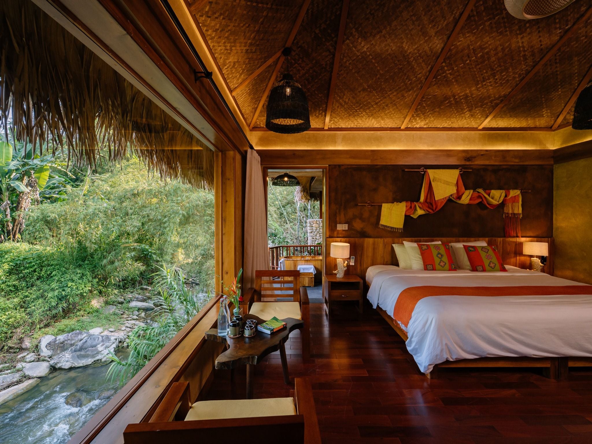 A room with a bed, bedside table, and a view of a natural landscape.