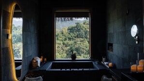 Une salle de bain avec une grande fenêtre, une baignoire, un miroir et un lavabo.