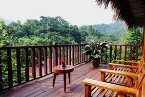 A wooden deck with a railing, a table, and two chairs. - An Chang Retreat & Spa (Ha Giang 1)