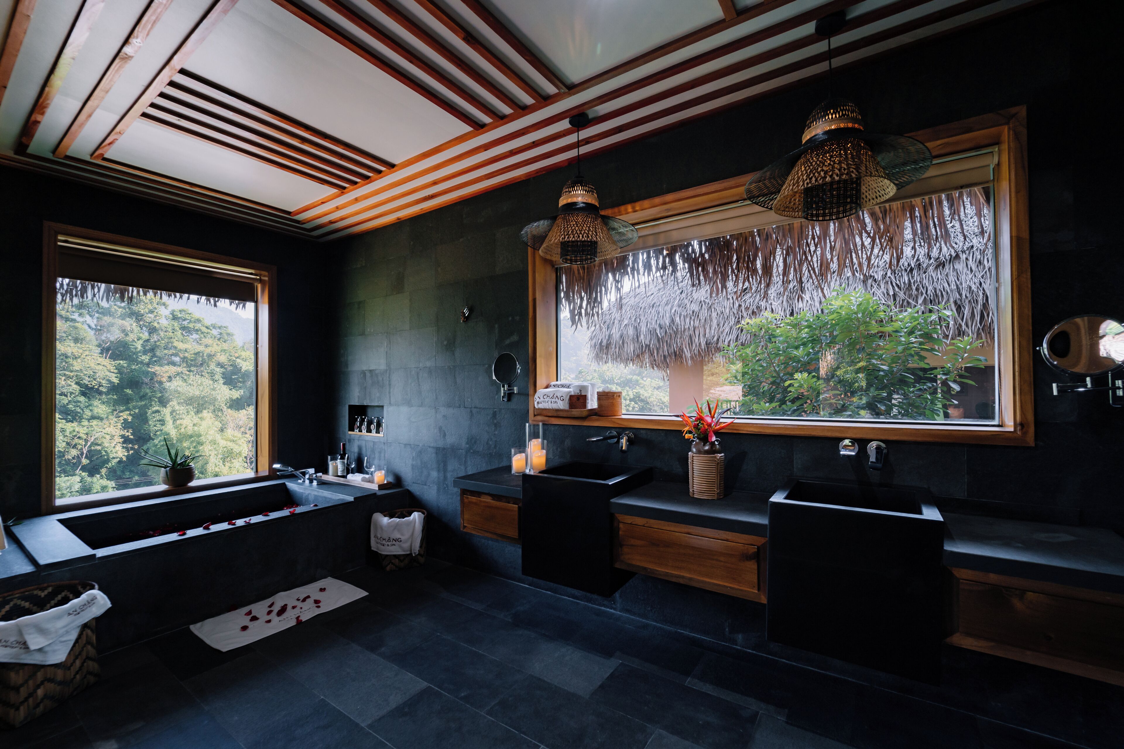 A modern bathroom with a large window, two sinks, and a bathtub.