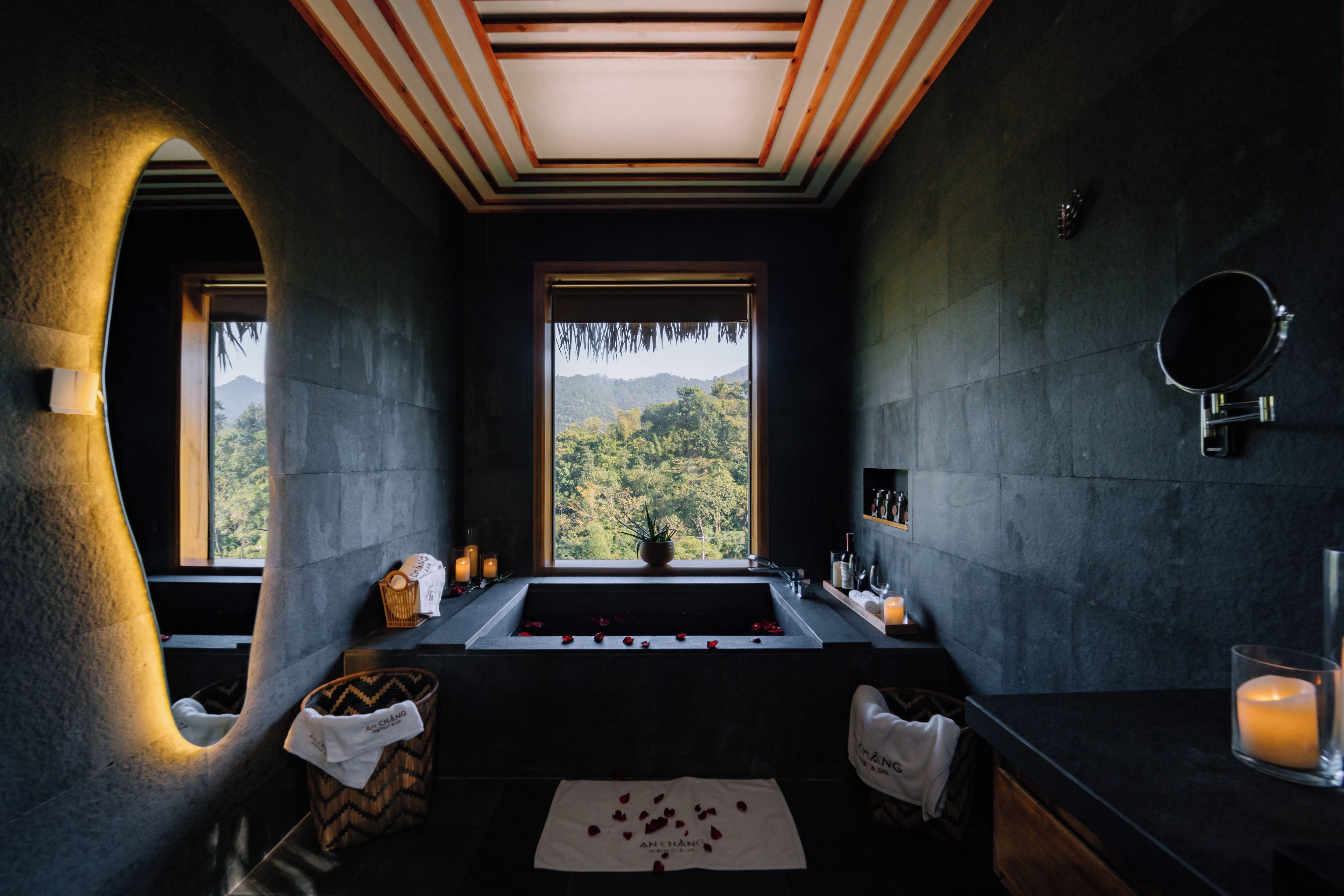 A modern bathroom with a large window, a bathtub, and a sink.