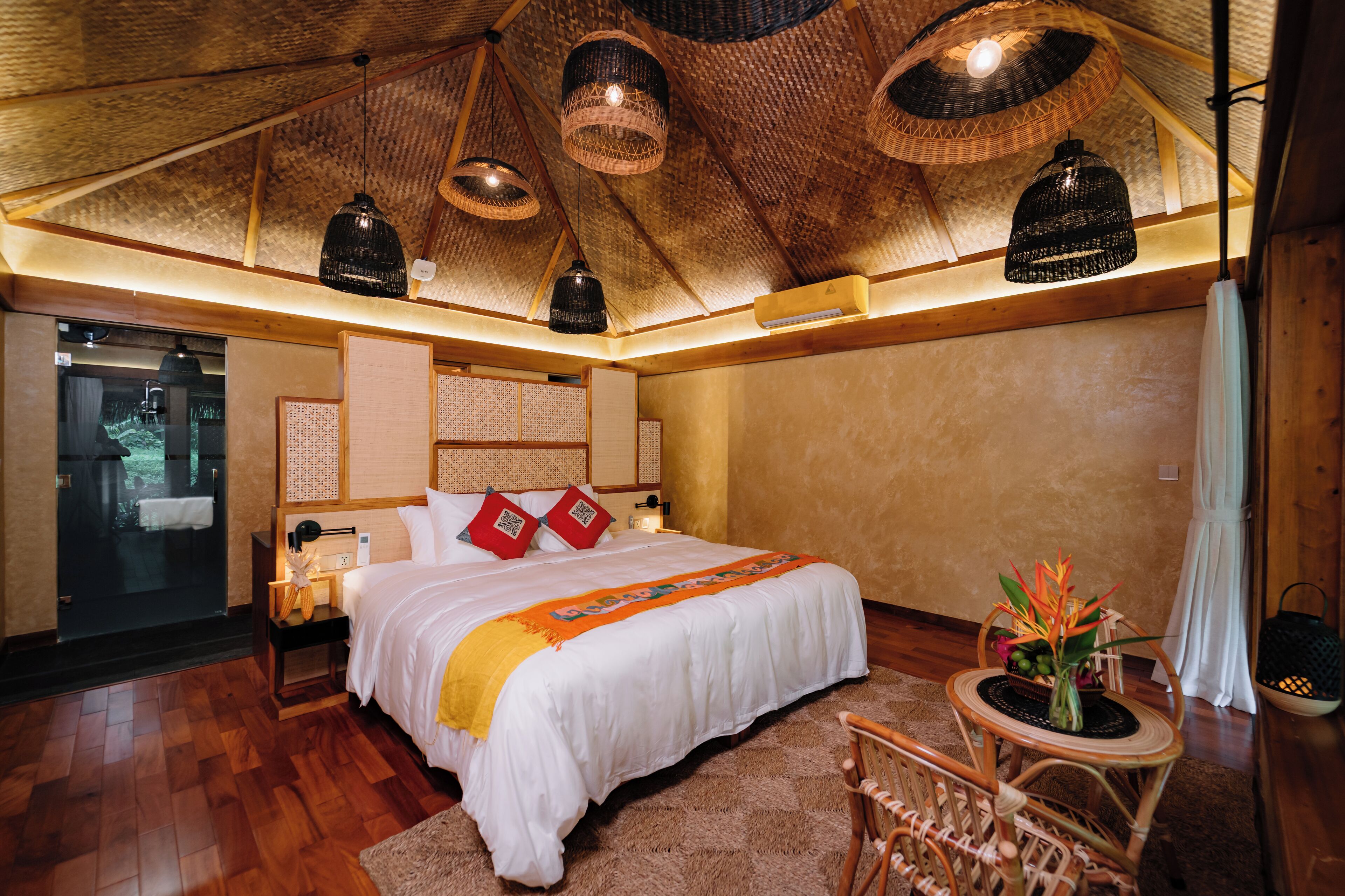 Un dormitorio amplio con una cama grande, techo de madera y vistas a un espacio exterior a través de un ventanal.