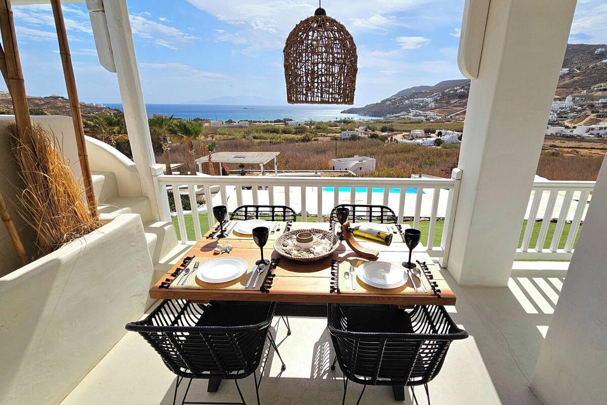 A table set for two with a view of the sea and hills in the background.