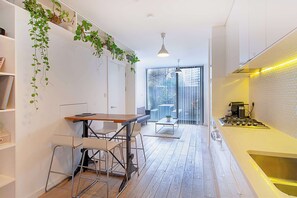 Une cuisine moderne avec une table en bois et des tabourets de bar, une cuisinière à gaz et une grande fenêtre donnant sur la ville.