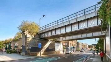 A street under a bridge with the sign 'QUEENS ROAD'.