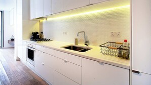 Eine moderne Küche mit weißen Schränken, einer Edelstahl-Spüle und einer gefliesten Spritzschutzwand.