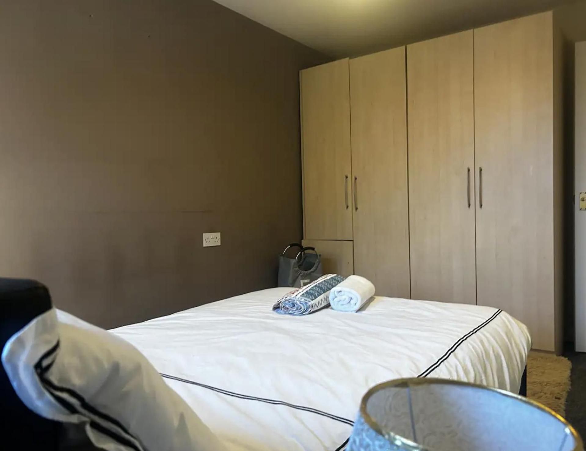A hotel room with a bed, a wardrobe, and a suitcase on the floor.
