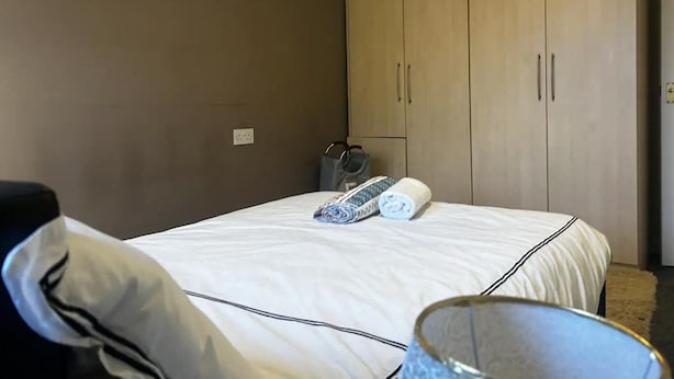 Ett sovrum med en säng, en garderob och ett litet bord med en lampa.