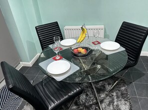 Een eettafel met vier stoelen, een schaal fruit en een banaan op de tafel.