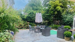 A patio with outdoor furniture, a table, and a green mat. - Affordable Charming and Spacious  1 bedroom in delightful Queens New York (Queens)