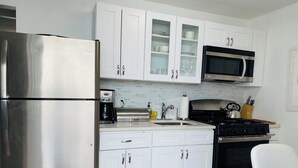 A modern kitchen with white cabinets, a stainless steel refrigerator, a coffee maker, a microwave, and a gas stove. - Affordable Charming and Spacious  1 bedroom in delightful Queens New York (Queens)