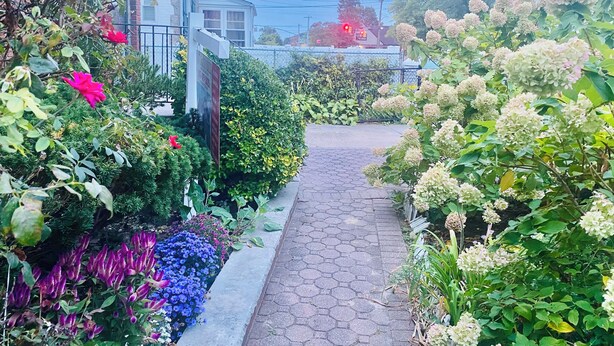 A garden pathway leading to a house with a brick exterior and a white door. - Affordable Charming and Spacious  1 bedroom in delightful Queens New York (Queens)