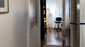 A narrow hallway with a wooden floor, a black cabinet, a white door, and a stainless steel refrigerator. - Affordable Charming and Spacious  1 bedroom in delightful Queens New York (Queens)