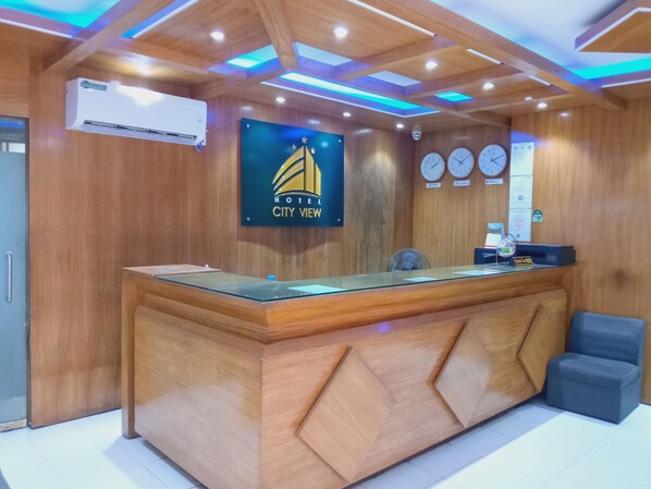 A hotel reception desk with a wooden finish, a digital clock, and a sign reading "HOTEL CITY VIEW". - Hotel City View (Dhaka)