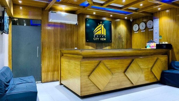 A hotel reception area with a wooden reception desk, a digital clock, and a sign that reads "HOTEL CITY VIEW". - Hotel City View (Dhaka)