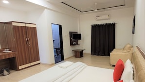 Una camera d'albergo con un letto, una scrivania, un armadio, una TV e un divano.
