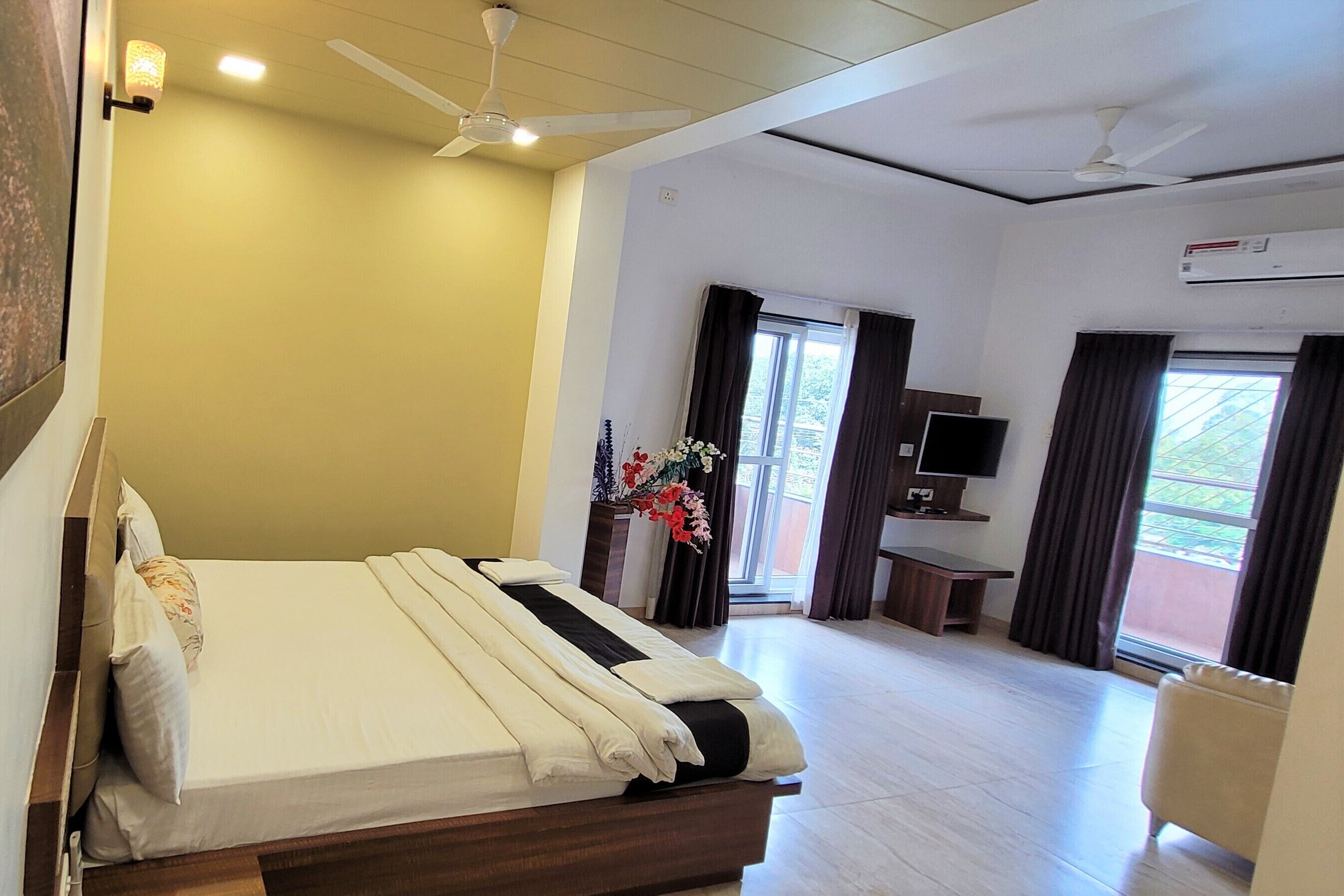 A hotel room with a bed, a desk, a TV, and a window with curtains.