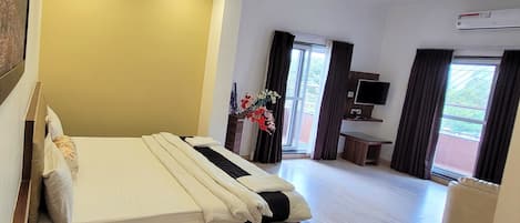 A hotel room with a bed, a desk, a TV, and a window with curtains.