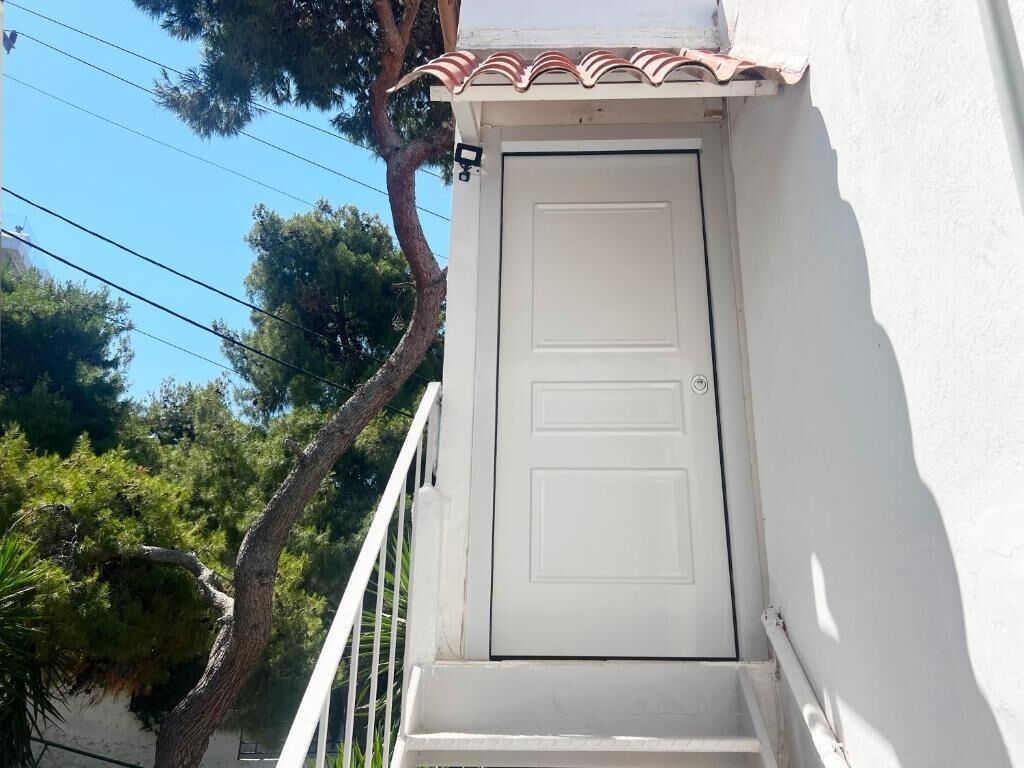 A white door with a small balcony and a tiled roof.