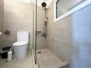Une salle de bain moderne équipée de toilettes, d’une douche et d’une porte en verre.