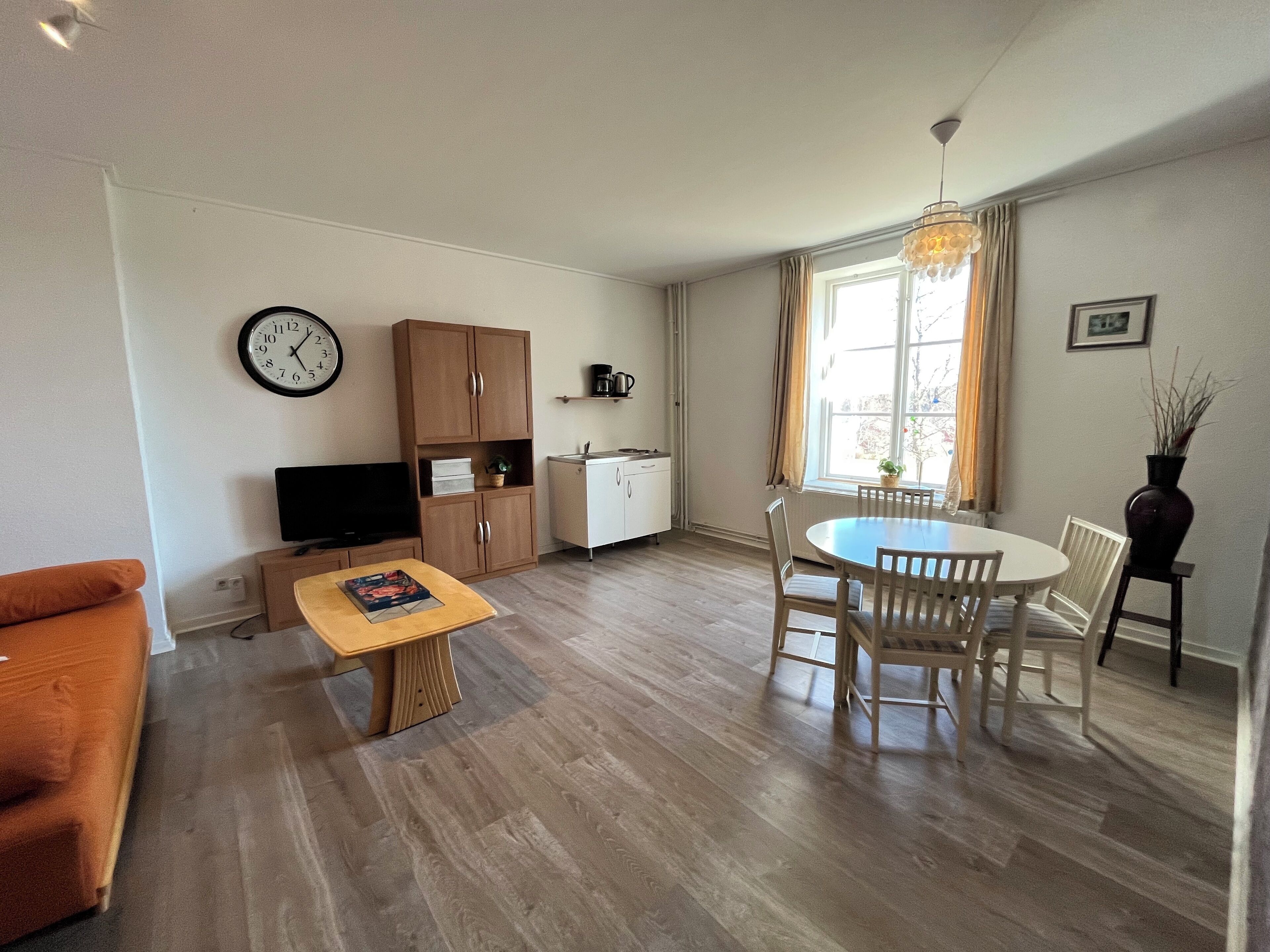 A compact living space with a dining area, kitchenette, and a TV.