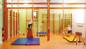Ein Fitnessstudio mit Holzeinrichtung, Matten und einem Basketballkorb.