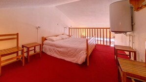 A bedroom with a wooden bed, two bedside tables, a red carpet, and a white ceiling. - Cozy apartment near slopes with parking (Les Menuires)