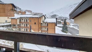A snow-covered mountain village with wooden buildings and a clear view of the mountains in the background. - Cozy apartment near slopes with parking (Les Menuires)