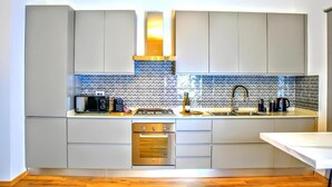 Una cucina moderna con pensili grigi, un lavello in acciaio inossidabile e un pannello di fondo decorato.