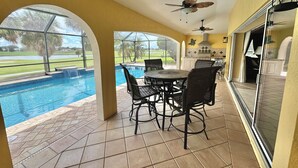 A covered patio with a pool, outdoor furniture, and a view of a golf course.