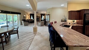 A spacious kitchen with a marble countertop, dark wooden cabinets, and a dining area with a round table and chairs.