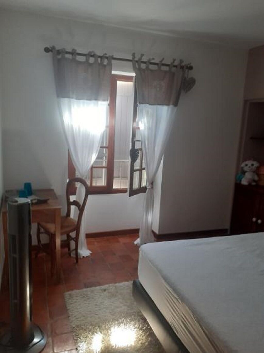 Un dormitorio con cama, escritorio, silla y ventana con cortinas.