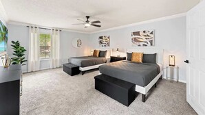 Un dormitorio moderno con dos camas, un ventilador de techo, obras de arte en las paredes y vistas al exterior.