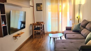 Un salon équipé d’un téléviseur à écran plat, d’un canapé, d’une petite table et d’une chaise.