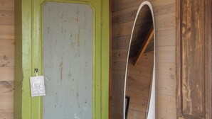 Une pièce avec une porte verte, une poubelle blanche et un plancher en bois.
