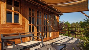 Une cabane en bois dotée d’un patio comprenant un banc et une table.
