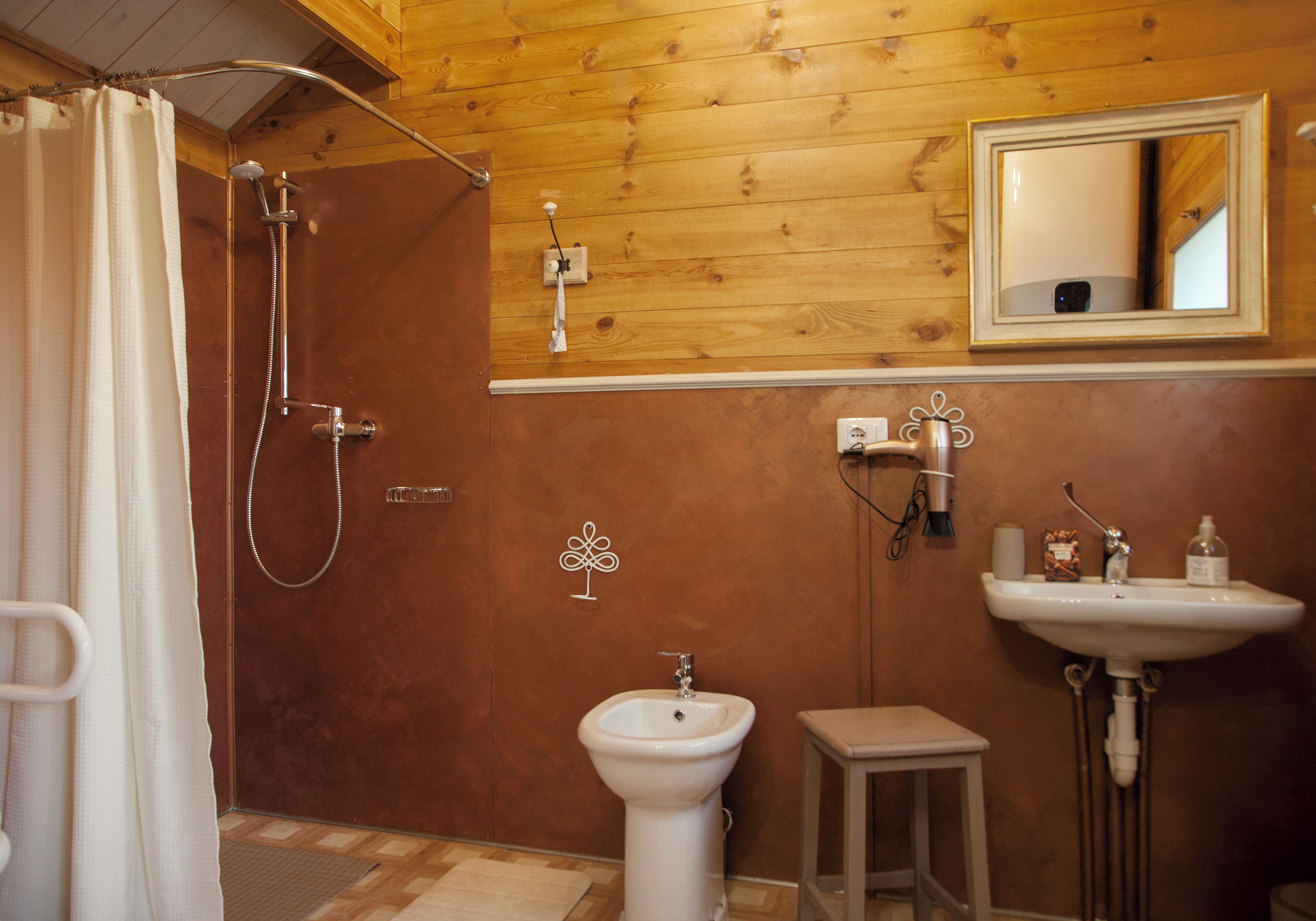 A wooden-paneled bathroom with a shower, a sink, and a mirror.