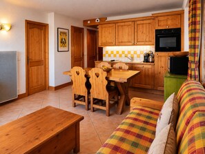 A compact kitchen with wooden cabinets, a dining table with chairs, a sofa, and a television. - Ski-in apartment 6 pers with pool and parking in Arc 1800 (Les Arcs 1800)