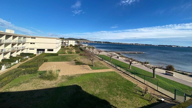 Een hotel aan de kust met uitzicht op zee, een boulevard en een parkeerplaats.
