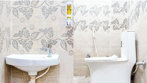 A bathroom with a white sink and toilet, a water heater, and floral-patterned tiles. - Hotel Kashi Grand Inn (Varanasi)