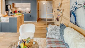 A cozy cabin interior with a kitchen, dining area, and a loft bedroom.