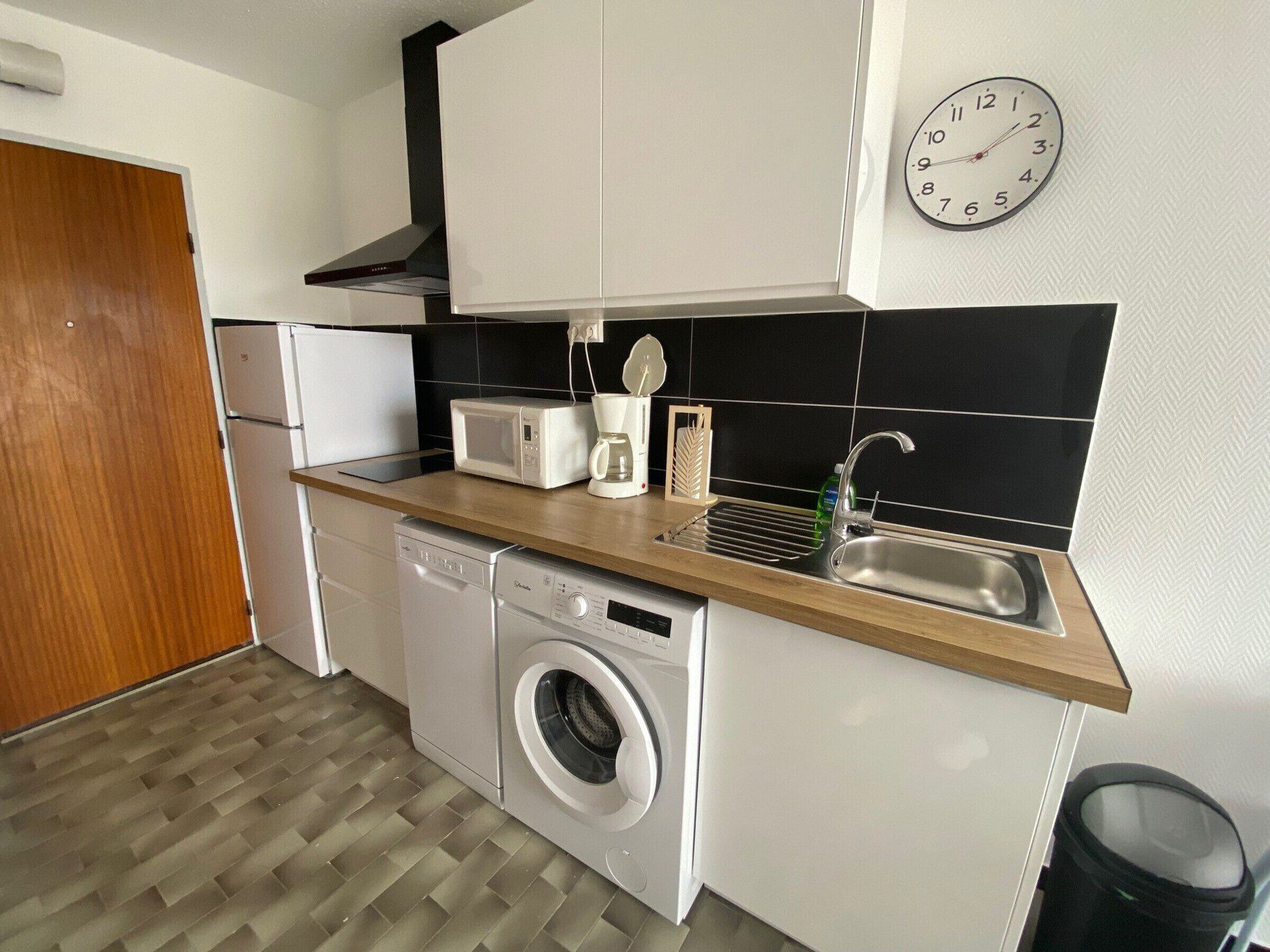 A compact kitchen with a microwave, coffee maker, and sink.
