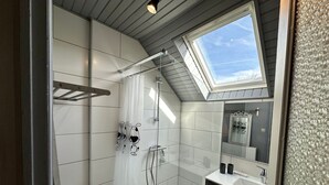 A modern bathroom with a skylight, white tiles, a shower, and a vanity with a mirror. - Bright duplex in the heart of Villard, 5 pax (Villard-de-Lans)