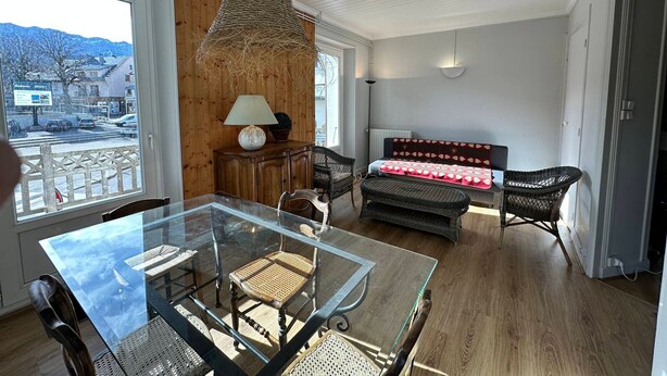 A modern living room with a glass dining table, wicker chairs, a sofa, and a view of the outside. - Bright duplex in the heart of Villard, 5 pax (Villard-de-Lans)