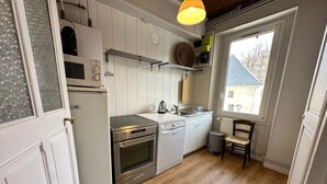 A compact kitchen with white cabinetry, a stainless steel oven, a dishwasher, and a window providing natural light. - Bright duplex in the heart of Villard, 5 pax (Villard-de-Lans)