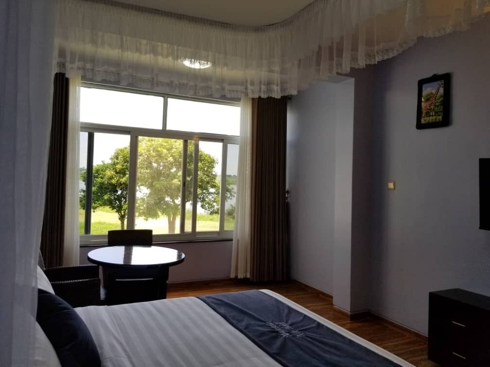 A hotel room with a bed, a round table, and a view of the outdoors.